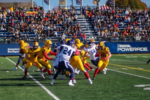 Players on a football field mid-game while a crowd watches
