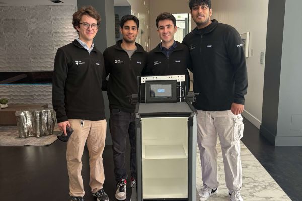 The co-founders of 3E8 Robotics pose with their autonomous robot, Elly, next to a cabinet and computer setup.