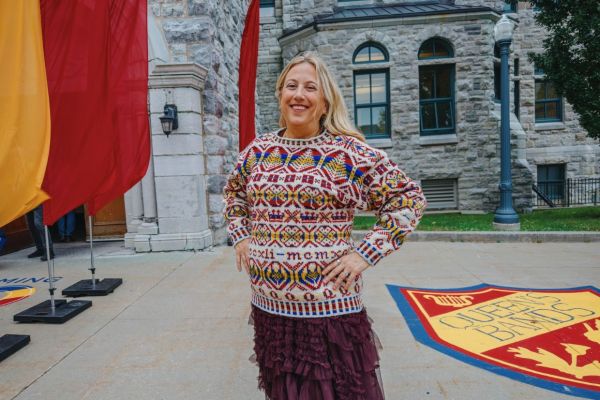 Allison Thistlewood, wearing a vibrant Homecoming 100 sweater, poses in front of Grant Hall.