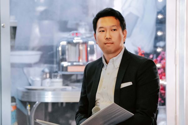 Jonathan Kong, Artsci’11, seated in a suit, holding papers while sitting in a chair.
