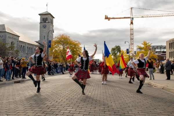 A lively street scene featuring people in kilts dancing joyfully, highlighting a festive atmosphere.