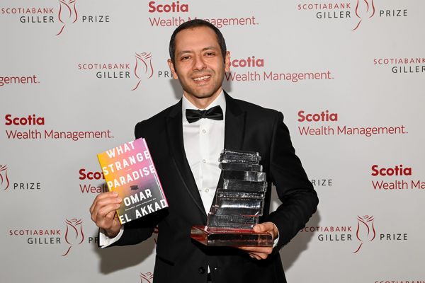 Omar El Akkad holding his novel and Scotiabank Gillar Prize award. 