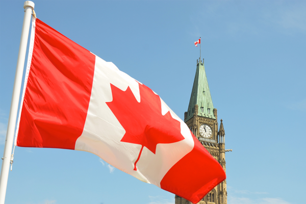 Canadian flag waving in front of Parliament. 
