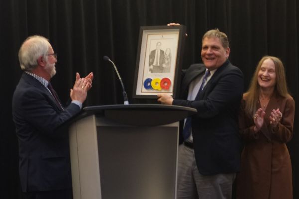 Principal and Vice-Chancellor Patrick Deane (left), presents a drawing to Principal Emeritus Daniel Woolf and his wife Julie Gordon-Woolf..