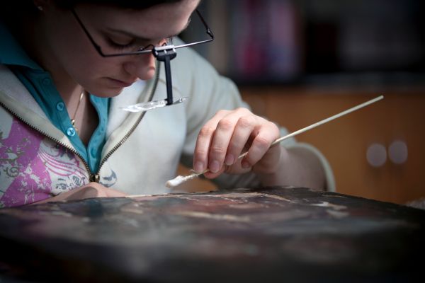 Student cleaning a painting