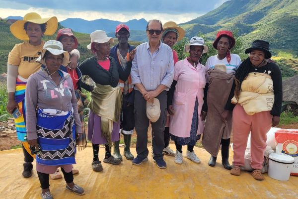 Tarek Elguindi posing with a women’s beneficiary focus group with green mountains in the background. 