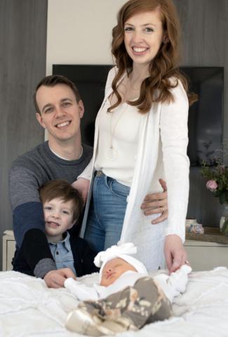 Brianna Guenther posing for a photo with her husband, Kevin, their little boy, and new baby girl.