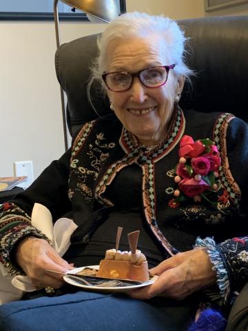 Donalda McGeachy sitting in a chair and posing for a photo with a piece of her birthday cake.