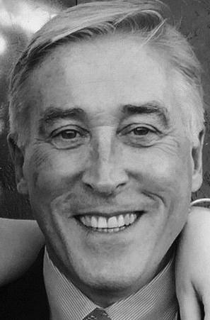 Black and white photo of a smiling Colin Sutherland from the neck up.