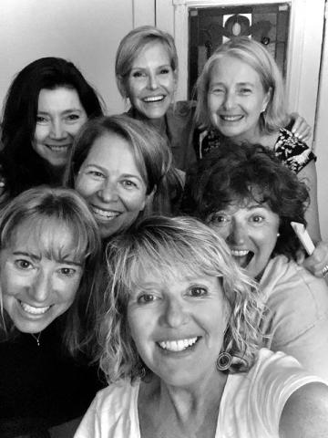 Group of eight women tucked in together close to take a selfie.