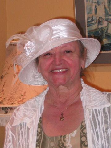 Woman wearing a white hat with satin and tulle flower on it.