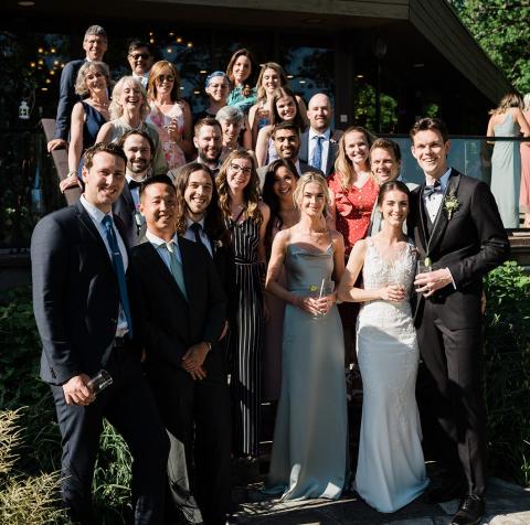Large wedding party standing outside in the bright sun.
