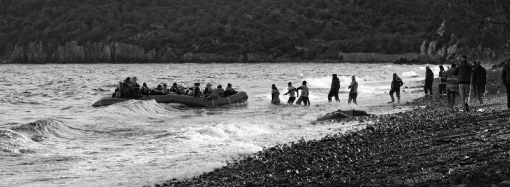 A raft filled with refugees is met by volunteers at Lesvos