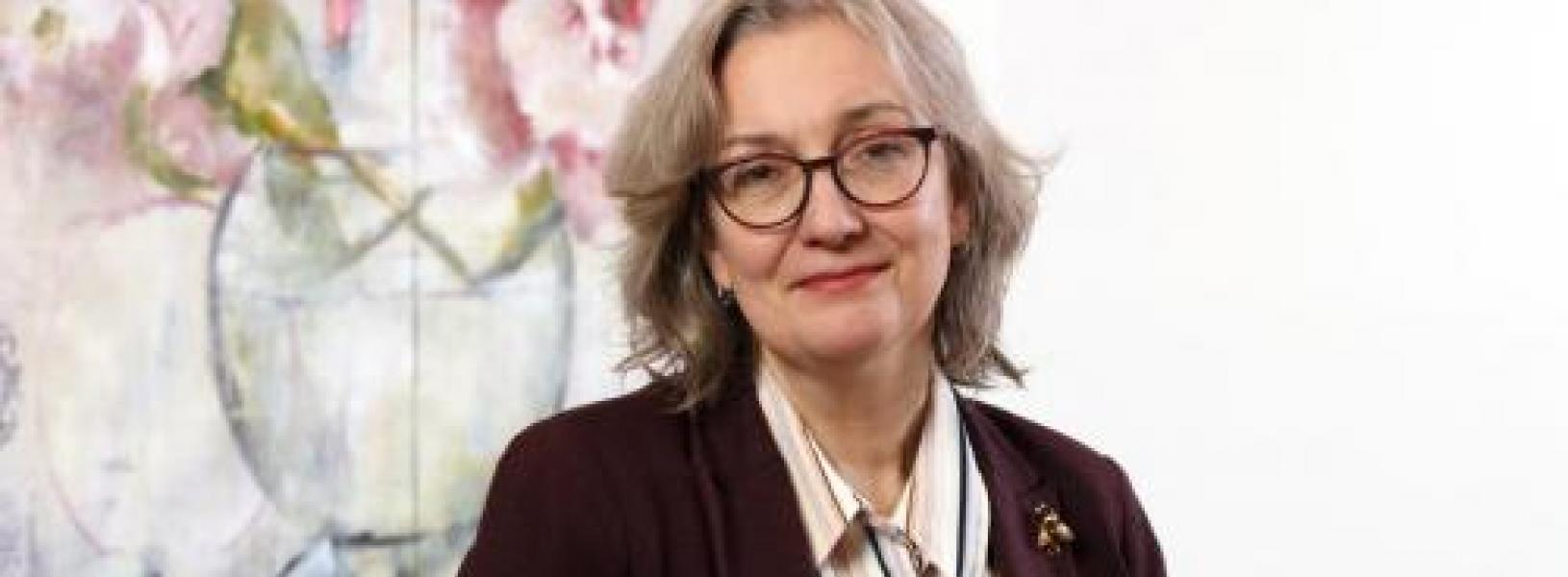 Photo of Andrea Gunn in front of a painting.