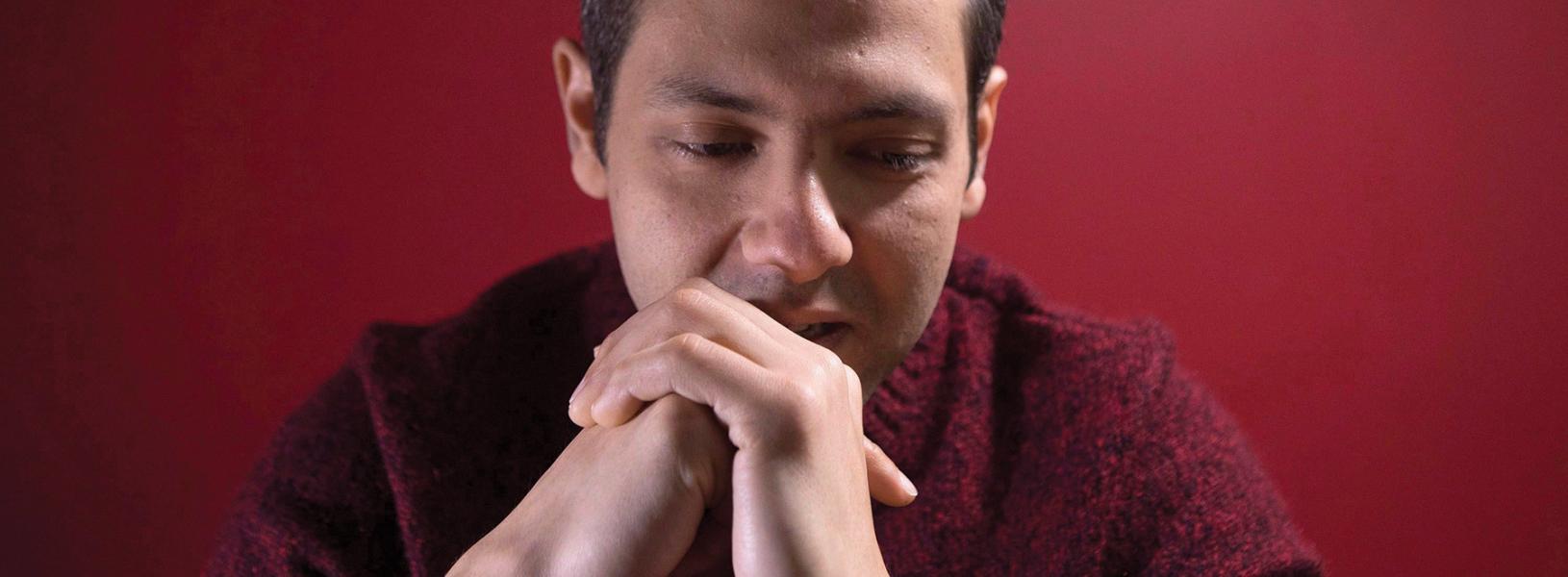 Omar El Akkad with hands folded over each other touching his chin