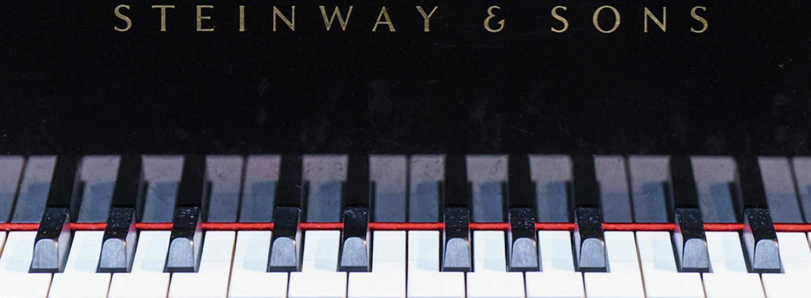 The keys of a Steinway piano looking head-on.