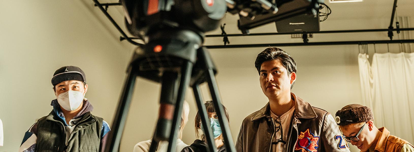 Several students gather behind a video camera, looking at the equipment, during a Sony workshop.