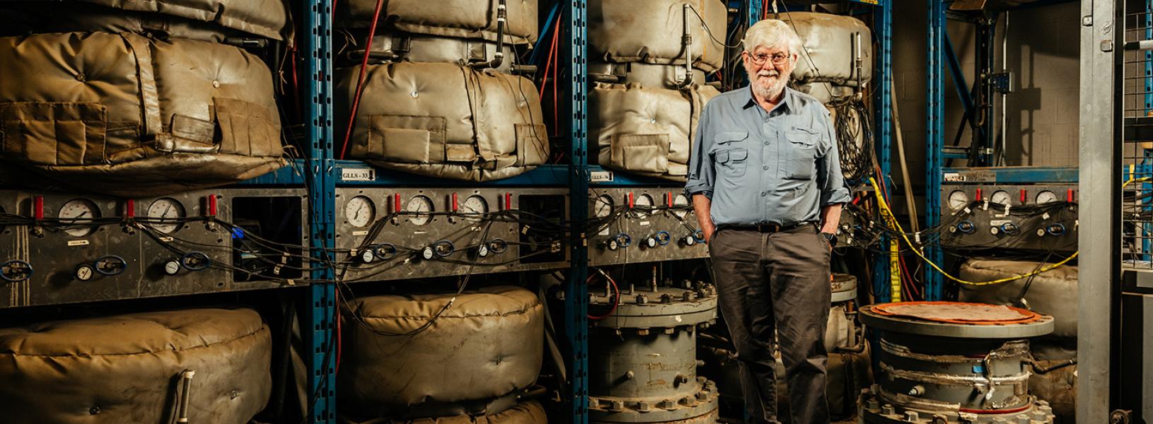 Dr. Kerry Rowe stands in front of shelving holding multiple landfill liners.