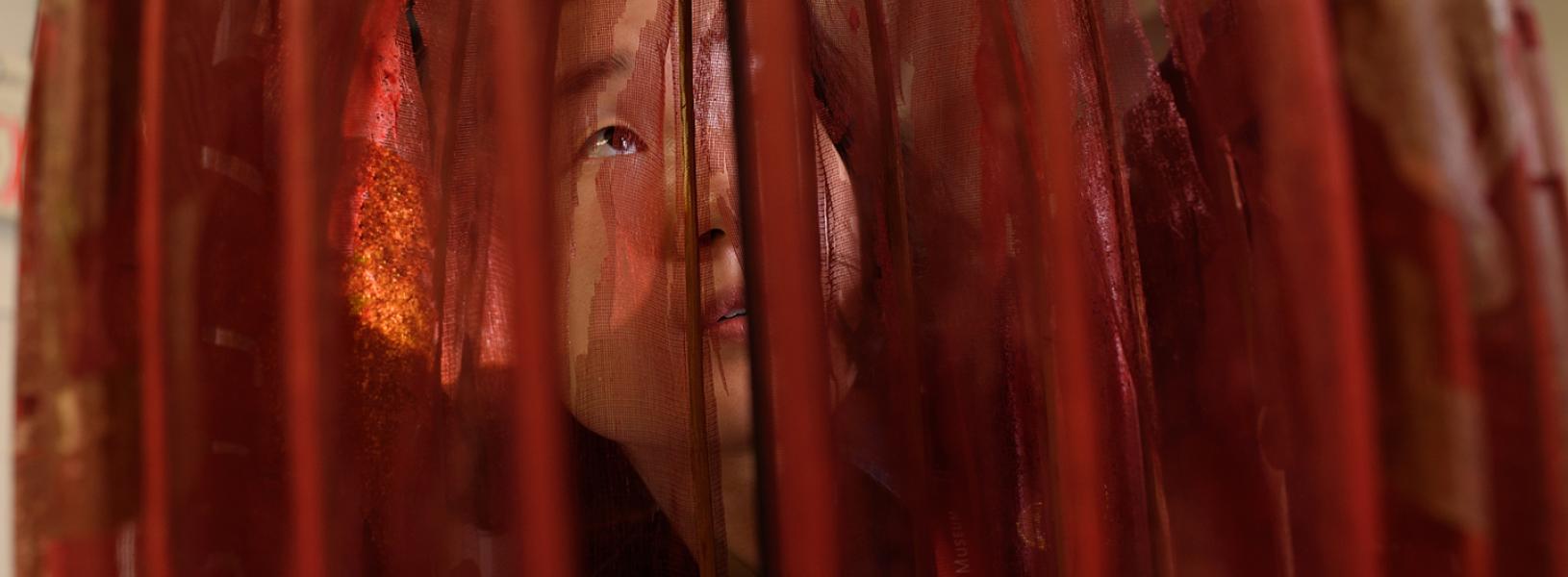 Woman looking through the fabric of a light fixture