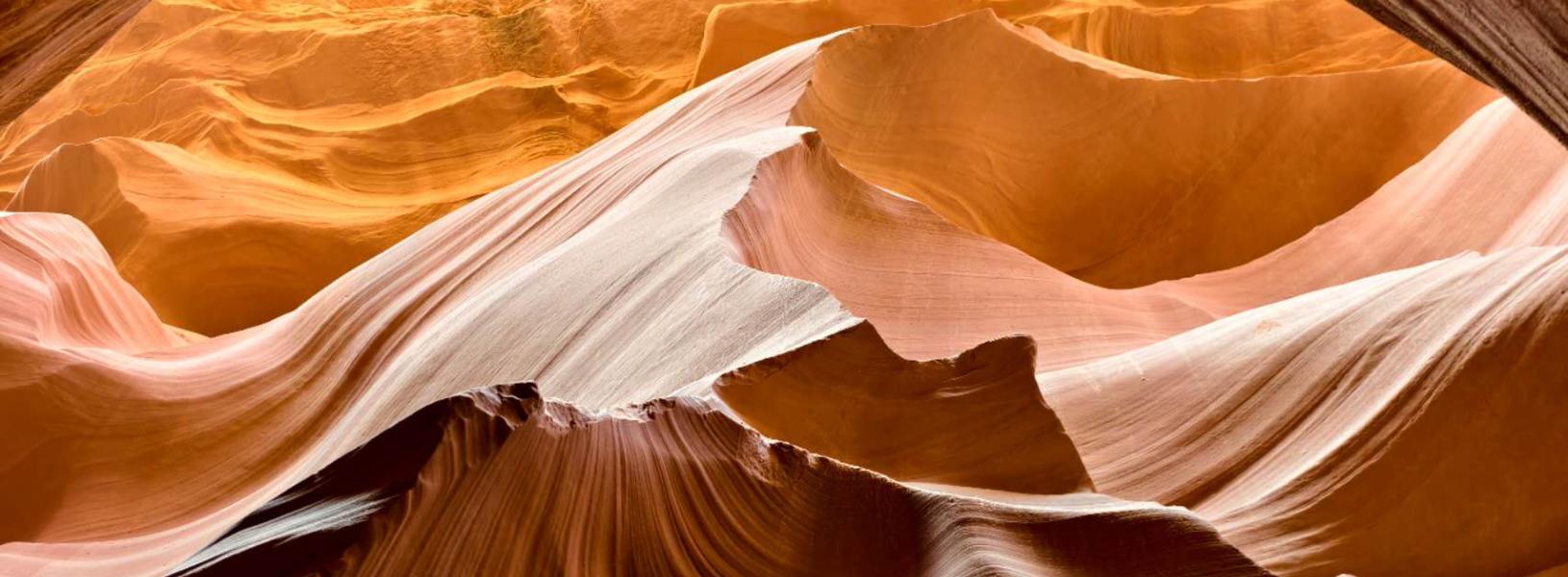 Sunlit sandstone formations and sweeping layered rock inside Antelope Canyon.