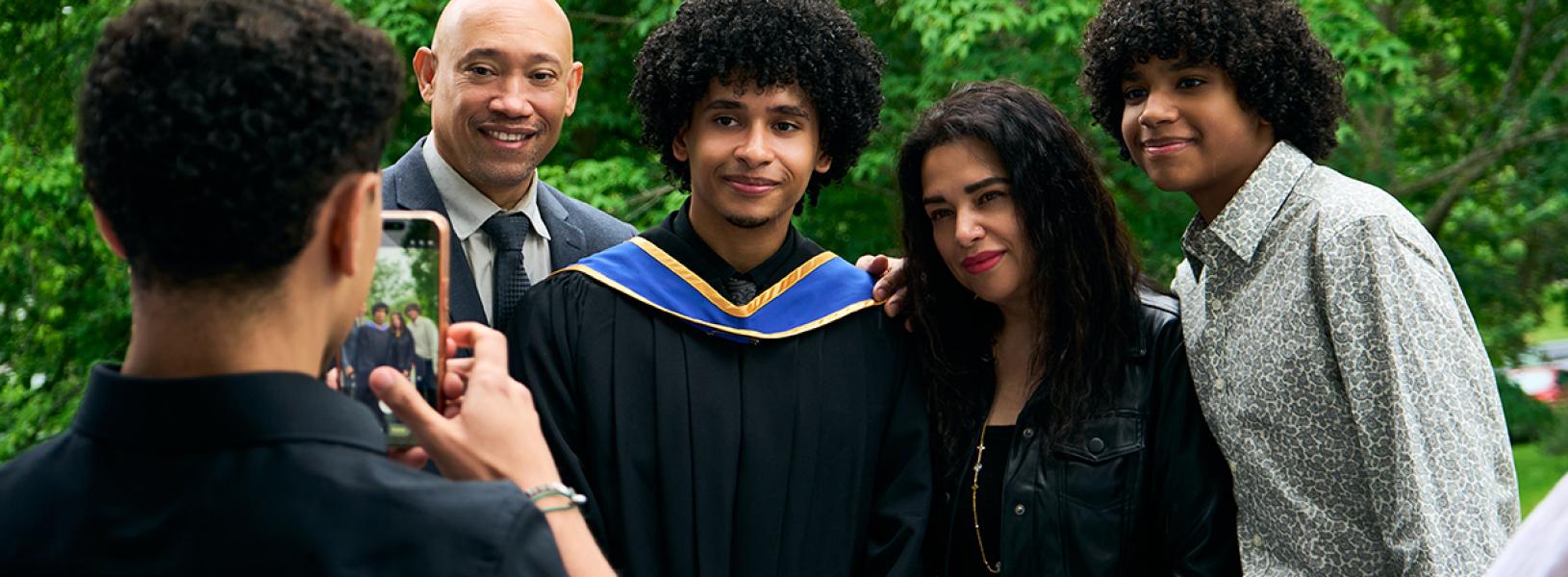 Graduate posing with family for a photo outdoors after a graduation ceremony.
