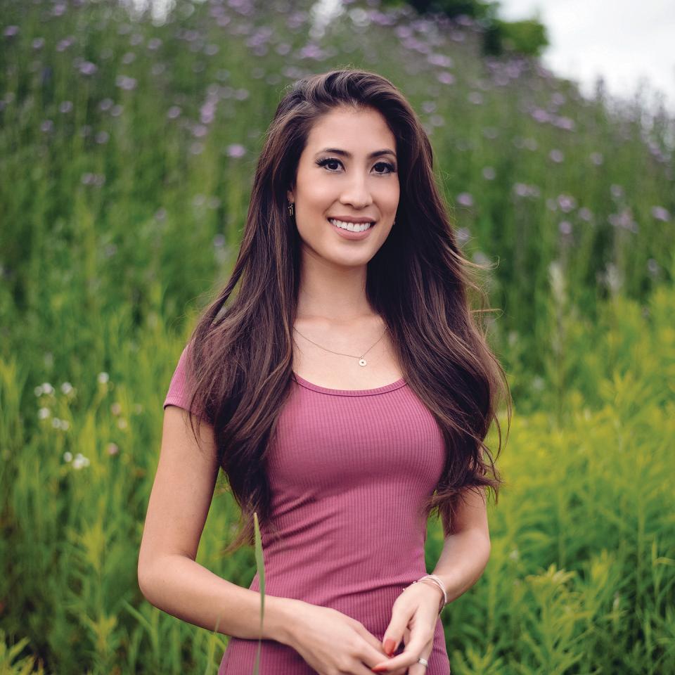 Photo of Miranda Anthistle standing in a field of wildflowers.