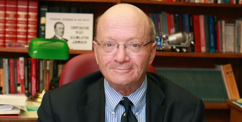 Man in a suit sitting at a table with a pen and paper in his hands