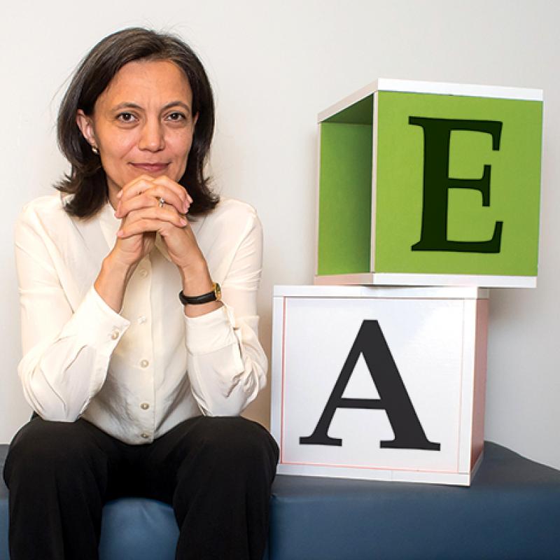 Dr. Stanka Fitneva, sitting on a bench in the lab, beside two large blocks with the letter A and E on them.