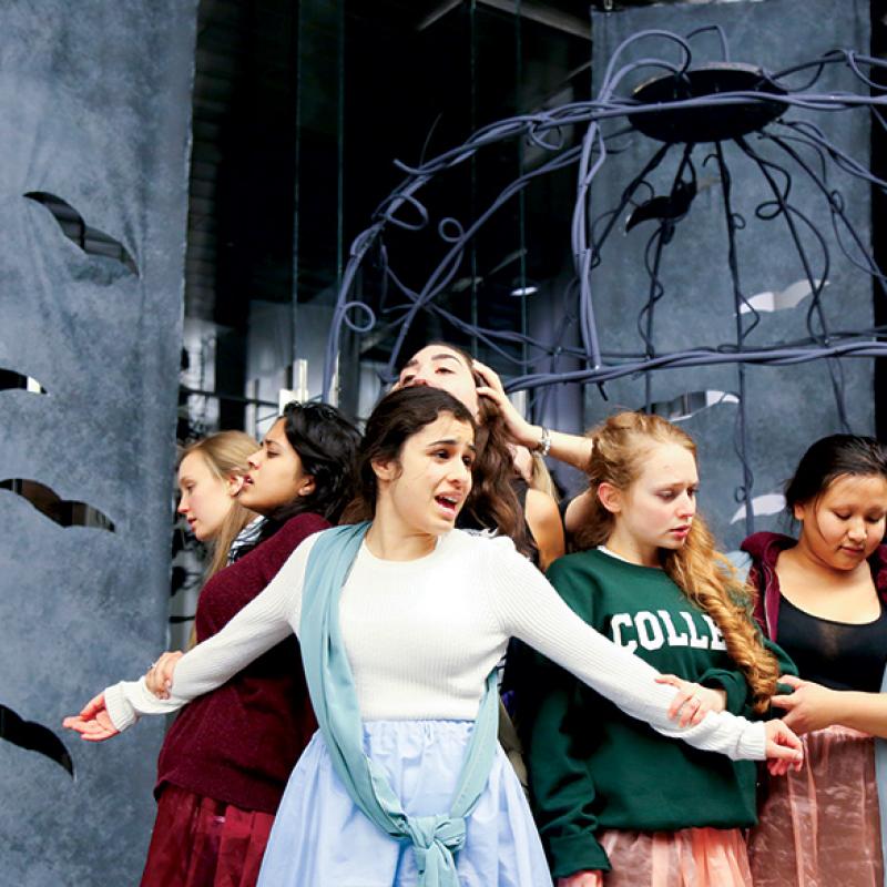 students in costume acting on stage with set and props