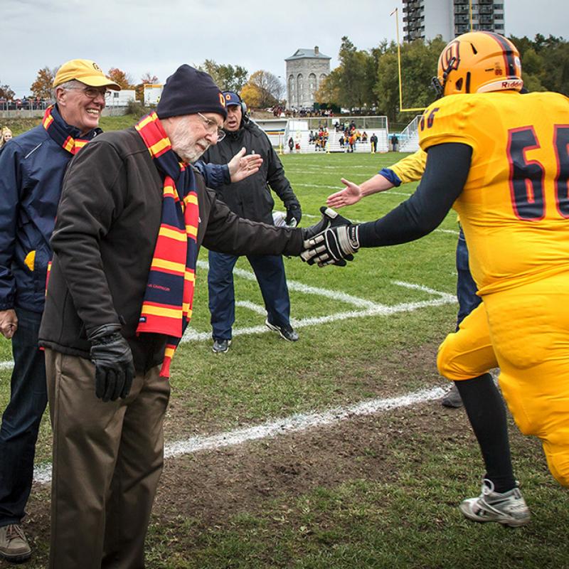 Dr. McDonald shaking hands with a football player during Homecoming