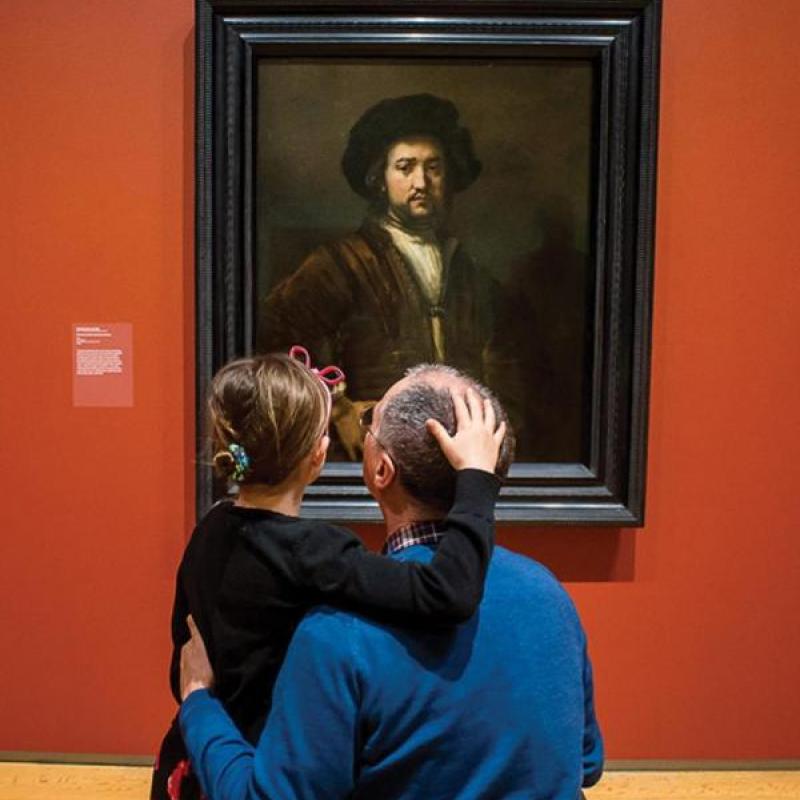 Daughter with father looking at a painting