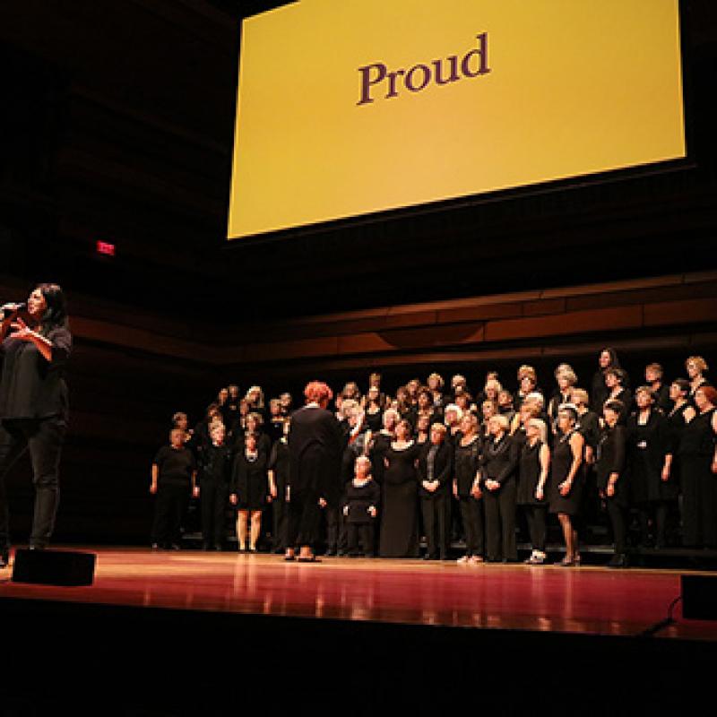 Group of people on stage with the word 'Proud' on screen