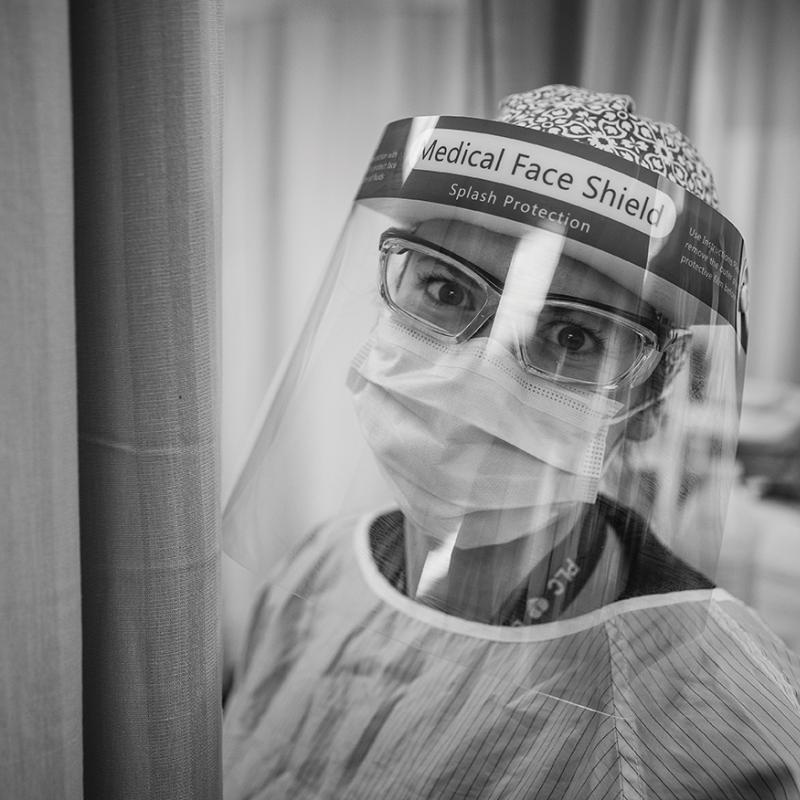 A medical worker looking at the camera in gown, mask, and face shield.