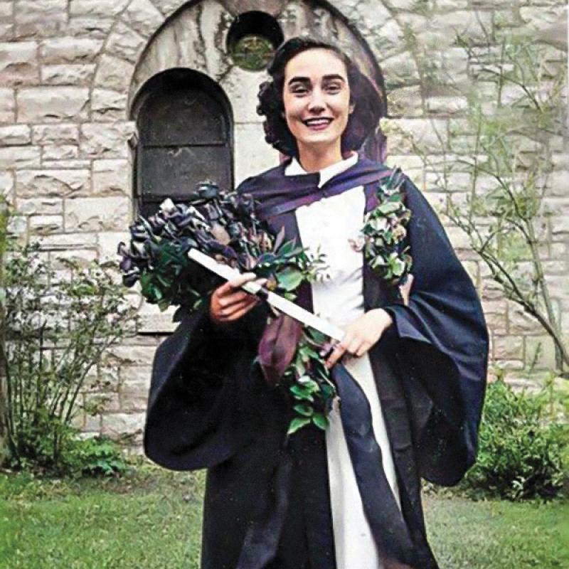 Colourized photo of Jean Tucker on graduation day, holding her diploma and flower.