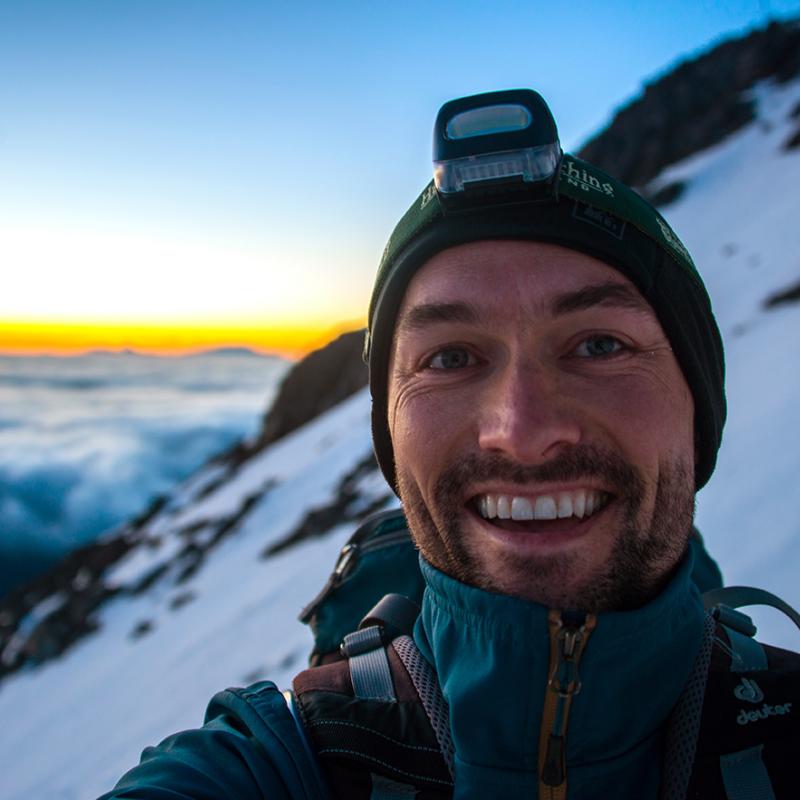 Chris Spencer taking a selfie on top of a snowy mountainside