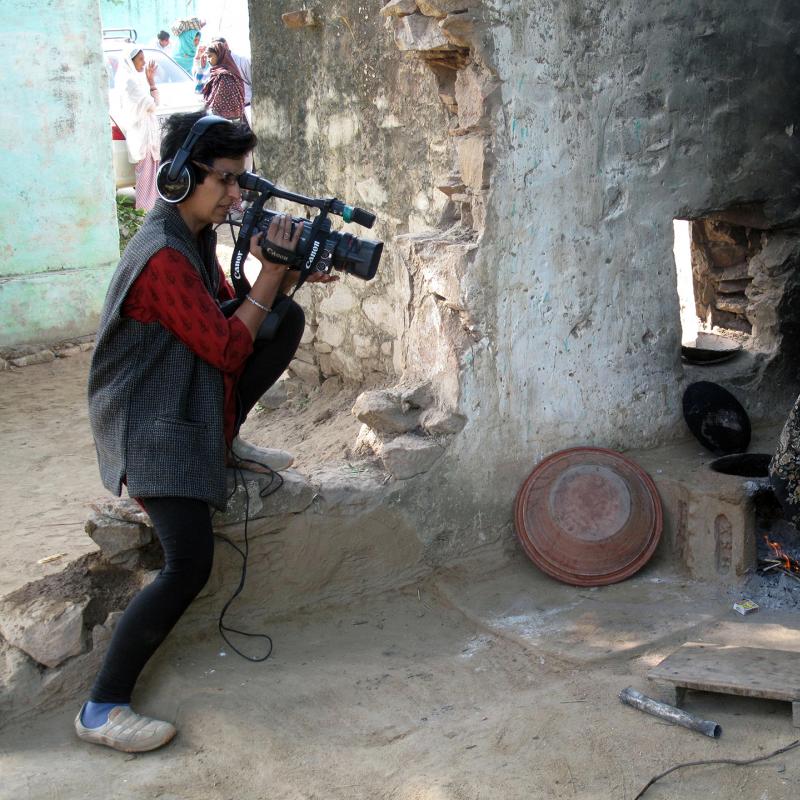 Reena Kukreja holds a video camera to her as she records a woman 