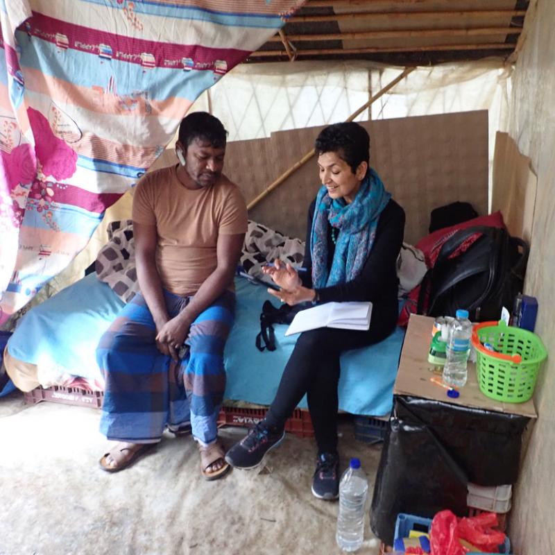 Reena Kukreja sits on the side of a makeshift bed while speaking with a migrant worker