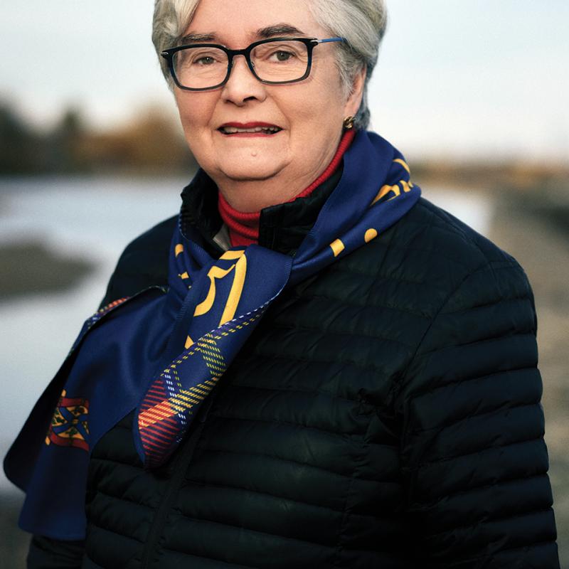 Brenda Drinkwalter standing outside in a winter coat and wearing a Queen's scarf.