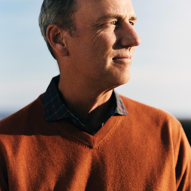 Brian Ames standing outside in a collared shirt and sweater, looking off to the side.