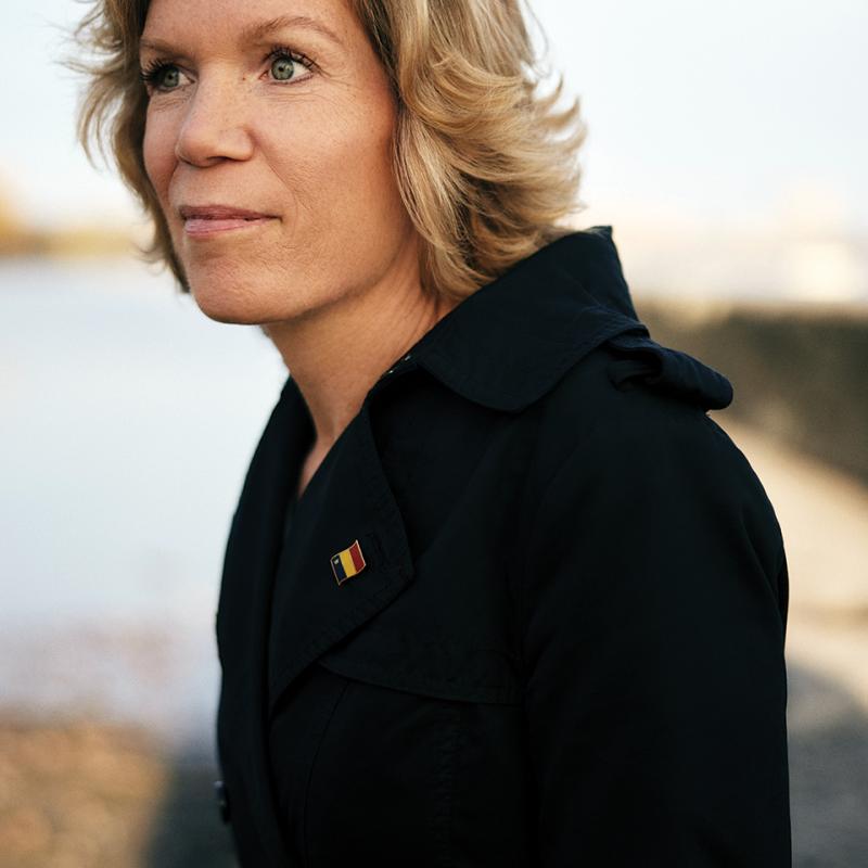 Heather Ferguson standing outside in a winter jacket, with a Queen's alumni pin on the lapel, looking off to the side.