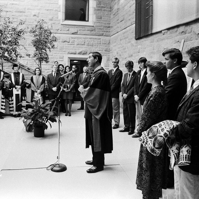 Prince Charles stands in front of a microphone speaking to a crowd at Queen's, October 1991.