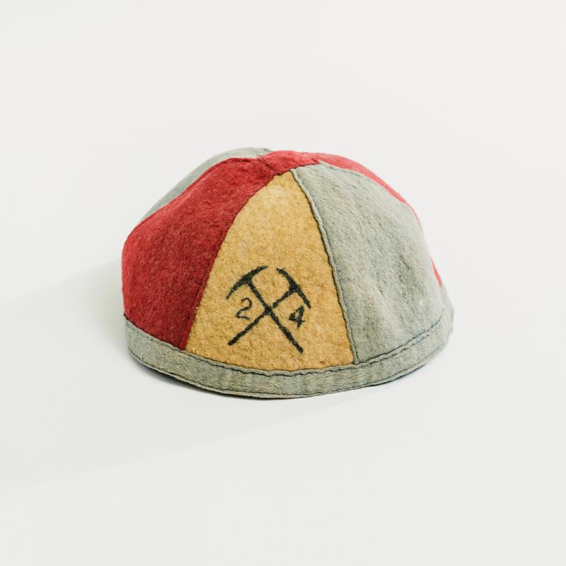 A vintage 1924 Queen's beanie, in alternating vertical Queen's colours, sits upright.