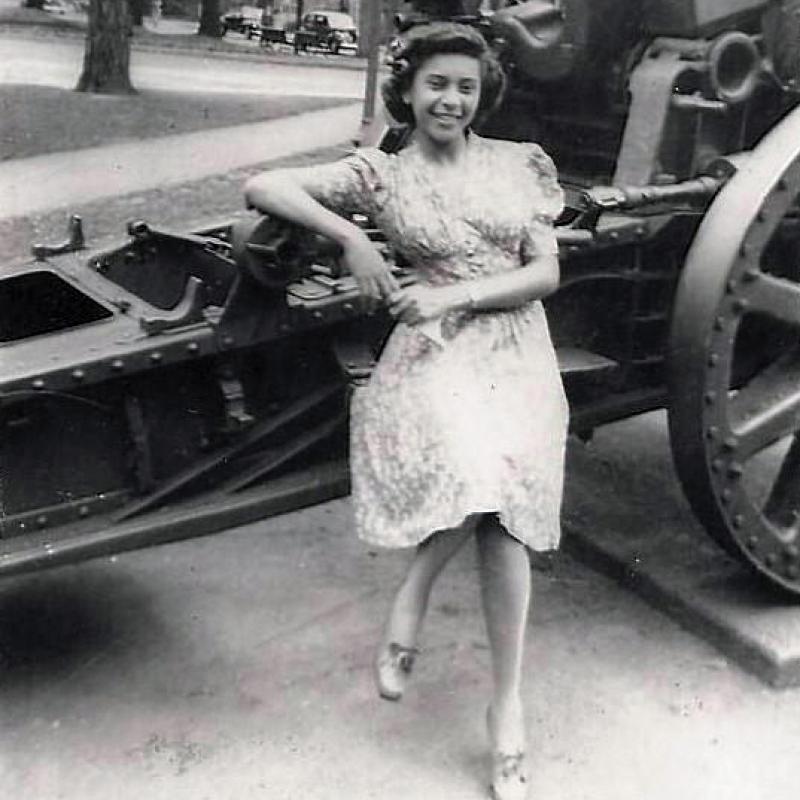 An old black and white photo of Elizabeth Kawaley sitting on some military machinery.