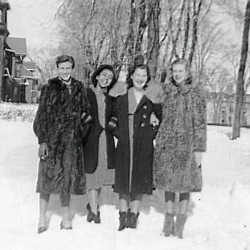 An old black and white photo of Elizabeth Kawaley, and three friends, standing in the snow in Kingston City Park.