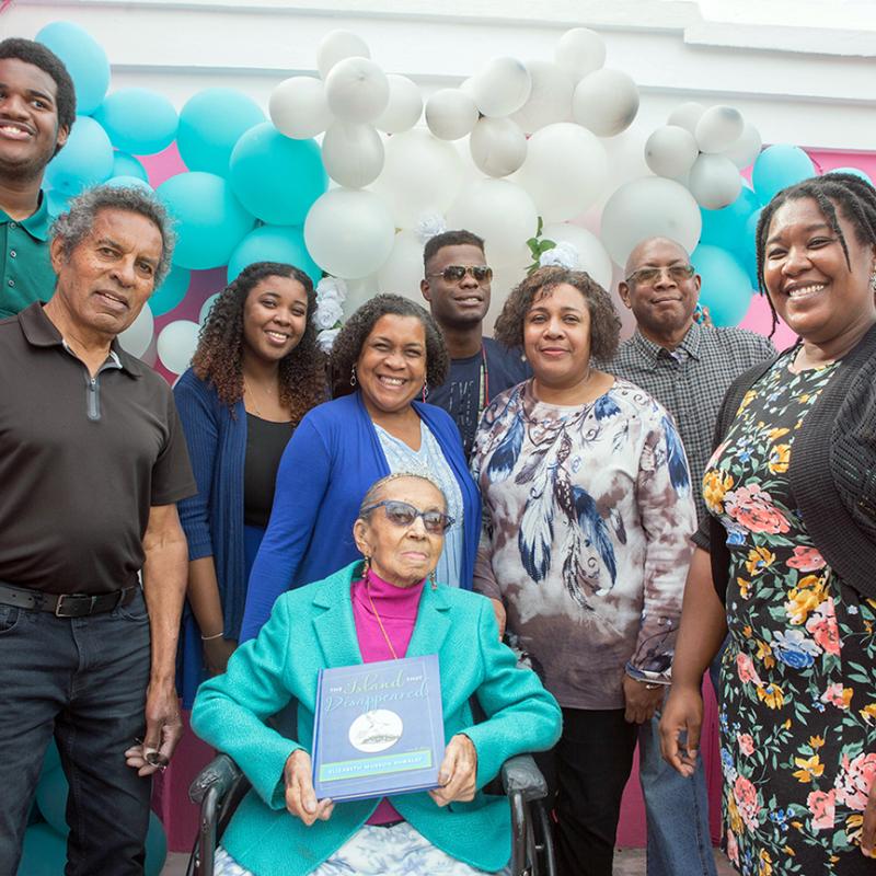Elizabeth Kawaley sits in a wheelchair, surrounded by family members. 
