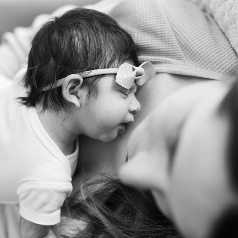 Newborn baby rests on mother's chest.