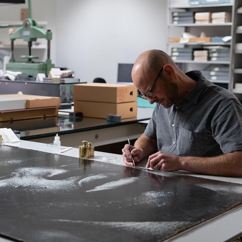Man works on a large piece of artwork