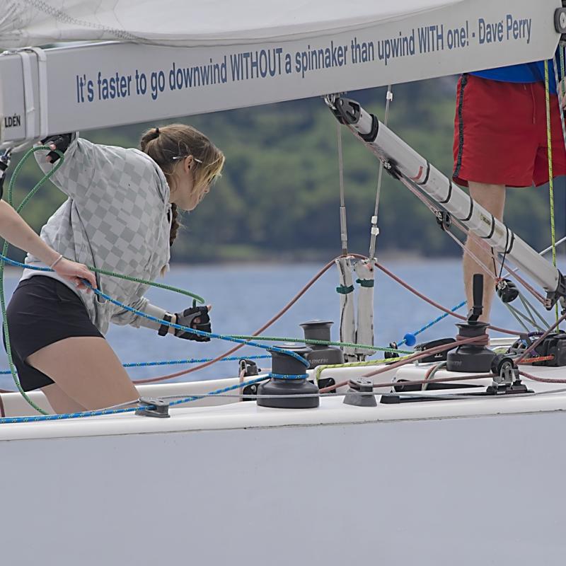 Three crewmembers of the Oakcliff Black sailboat work on the boat.