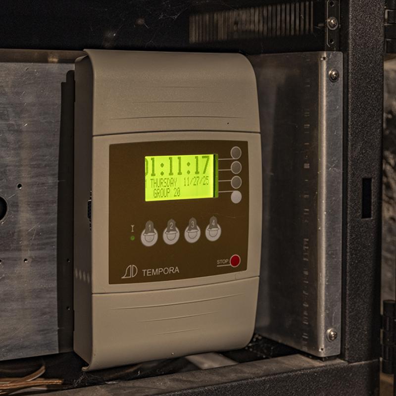 Digital clock control unit mounted inside the tower, displaying time and date on a green screen.