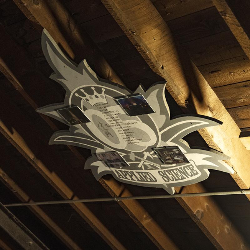 Decorative “Applied Science” crest mounted against wooden beams inside the tower.